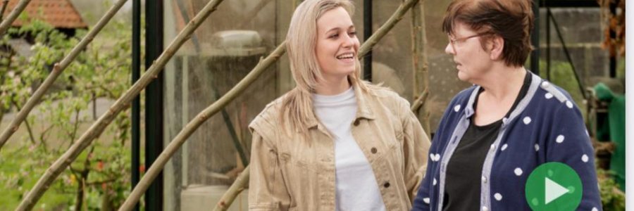 twee dames kijken elkaar lachend aan, staan buiten